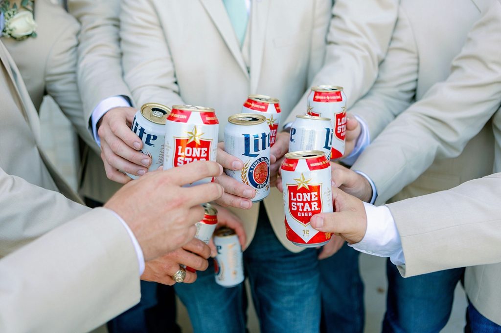 groom and groomsmen cheers with lone star beer cans on wedding day